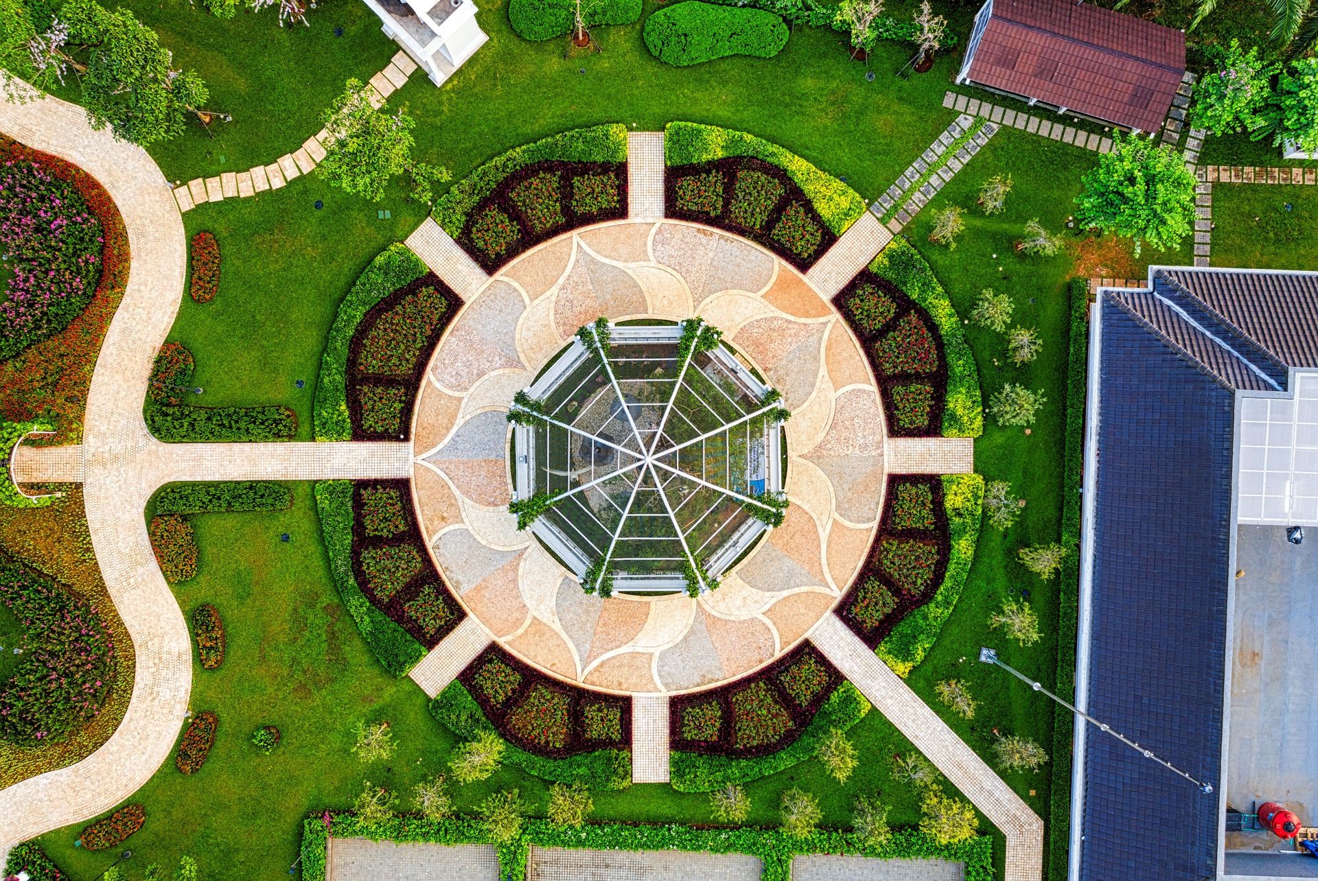 Aerial view of a circular formal garden with radiating paths, clipped hedges and flower beds around a central pavilion
